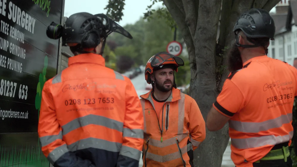 A GraftinGardeners tree surgery crew of three in branded hi-vis on a London street A GraftinGardeners tree surgery crew of three in branded hi-vis on a London street