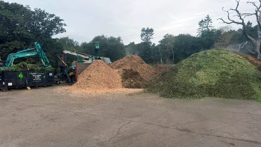 Large piles of wood chip and green waste with processing machinery at our Surrey green waste re-cycling centre